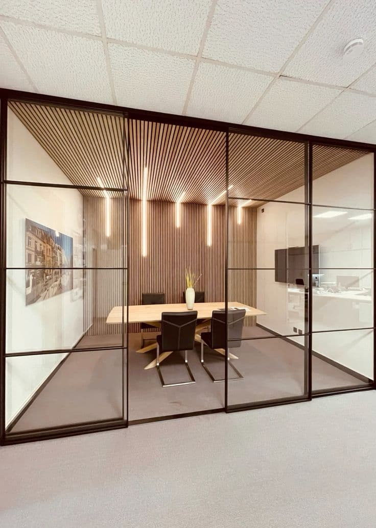Glass meeting room with wooden table, black chairs, and slatted wood ceiling with vertical lights.